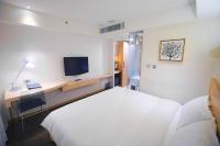 a hotel room with a bed and a desk and a television at Beacon Hotel in Taichung