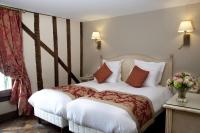 a hotel room with a bed with white sheets and orange pillows at Auberge Saint Pierre in Le Mont Saint Michel