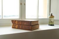 a stack of books sitting on a shelf next to a window at Mas des Coteaux - vue panoramique - piscine - babyfoot - pingpong - pétanque &amp; espace enfants à 1h de MONTAUBAN in Gramont