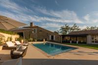 a swimming pool with chairs and an umbrella next to a house at Mas des Coteaux - vue panoramique - piscine - babyfoot - pingpong - pétanque &amp; espace enfants à 1h de MONTAUBAN in Gramont