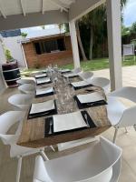 a long wooden table and white chairs on a patio at Villa Anse Vinaigri - Plage à pieds in Le Gosier