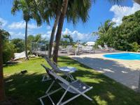 a pair of lawn chairs sitting next to a swimming pool at Villa Anse Vinaigri - Plage à pieds in Le Gosier