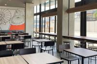 a dining room with tables and chairs and windows at Amaris Hotel Kalimalang in Jakarta