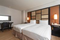 a hotel room with a large white bed and a desk at Beitou Sweet Me Hot Spring Resort in Taipei
