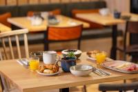 einen Holztisch mit Teller mit Speisen und Orangensaft in der Unterkunft ibis Styles Les Houches Chamonix in Les Houches