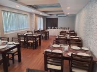 een eetkamer met houten tafels en stoelen en een kamer met een buffet bij Serene Sriperumbudur in Kāndūr