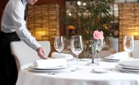 a man is setting a table with a white table cloth at A Quinta Da Auga Hotel Spa Relais & Chateaux in Santiago de Compostela