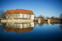 un edificio con techo rojo junto a un río en Michel Hotel Landshut Kaiserhof, en Landshut
