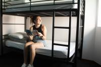 a woman sitting on a bunk bed reading a book at Nomads St Kilda in Melbourne