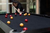 a man playing pool with balls on a pool table at Nomads St Kilda in Melbourne