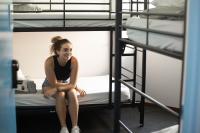 a woman sitting on a bed in a bunk room at Nomads St Kilda in Melbourne