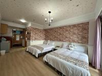 a bedroom with two beds and a brick wall at MB Hotel in Kaohsiung