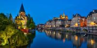 a river in a city at night with buildings at LES MIRABELLES in Metz