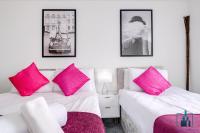 two beds in a room with pink pillows and a chair at City View Apartments Birmingham City Centre in Birmingham
