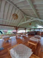 Un gran pabellón con bancos y mesas sobre un suelo de madera. en Pondok Indah Bungalows Tetebatu, en Tetebatu