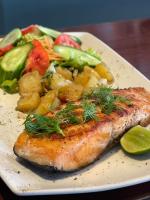 een bord voedsel met een stuk vis en groenten bij San Antonio Beach Guesthouse & Restaurant in Kata Beach