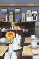 a table with white vases with a yellow flower in them at IntercityHotel Bonn in Bonn