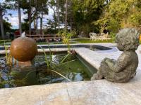 a statue of a little boy sitting next to a pond at Mas de la Sacristière in Jonquerettes