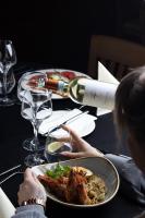 シュチルクにあるHotel META Resort & Vine SPAの食べ物の皿を持ってテーブルに座っている女性