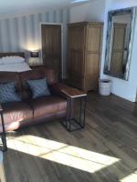 a living room with a brown leather couch and a bed at Garden Suite in Rhuddlan