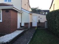a brick house with a white door and a yard at Garden Suite in Rhuddlan