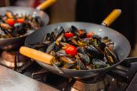 two frying pans filled with mussels and tomatoes on a stove at International Hotel Casino & Tower Suites in Golden Sands