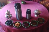 a pink table with bowls of food and a thermos at Erg Chigaga Regency Camp in El Gouera