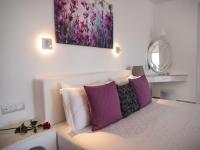 a bedroom with a bed with purple and white pillows at Vitsentzos Suites in Imerovigli