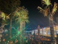 a group of people sitting at tables under palm trees at night at Hotel Venus in Venus