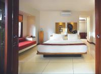 a bedroom with a large white bed and a red couch at Qunci Villas Resort in Senggigi