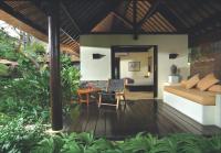 a room with a bed and a wooden deck with a table at Qunci Villas Resort in Senggigi