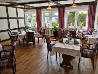 a dining room with tables and chairs and windows at Hotel Zum Märchenwald in Lingen