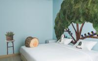 a bedroom with a bed with a tree mural on the wall at Beat Hotel Bangkok in Bangkok