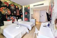 a room with two beds and a wall with flowers at Beat Hotel Bangkok in Bangkok