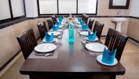 a long wooden table with blue napkins and chairs at The Altruist Business Stays, Navi Mumbai-2 in Ghansoli