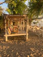 Un cenador de madera con sillas y mesas en una playa. en Gili Air Santay Bungalows, en Gili Air