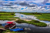 um barco ancorado em um rio em um campo em Kubu & Kwena Lodge em Katima Mulilo