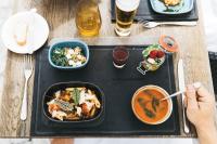 Una mesa con una bandeja de comida y una persona sosteniendo una cuchara. en Hotel Sandwirth, en Klagenfurt