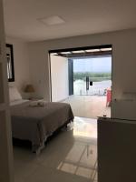 a bedroom with a bed and a large glass window at Suítes Luxo Marambaia- Epic House in Rio de Janeiro