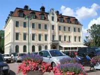 Un gran edificio blanco con coches aparcados en un estacionamiento. en Eksjö Stadshotell, en Eksjö