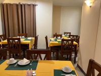 un comedor con mesas amarillas y sillas de madera en Anglo Hotel, en Luxor