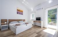 a white bedroom with a bed and a television at 3 Bedroom Amazing Home In Plomin in Plomin