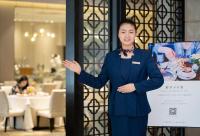 広州市にあるMehood Lestie International Hotel Linhexi Guangzhou East Railway Station Branch - Free Shuttle Bus to Canton Fair Complex During Canton Fair Period & Free Deliver Service to Guangzhou Baiyun International Airport & Free VPN Internet Accessの看板の横に立っている青いスーツを着た女性