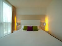a large white bed with green and purple pillows at Pisa Tower Plaza in Pisa