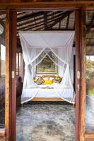 a canopy bed with a white mosquito net at Tano Home Villas in Ubud