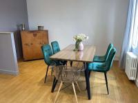 a wooden table with green chairs and a vase of flowers at En_Terre_Champenoise Epernay in Épernay