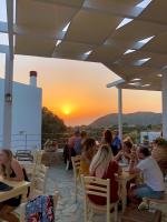 a group of people sitting at tables watching the sunset at Mourtzanakis Residence - Traditional Eco Hotel in Achlada in Achlada