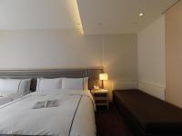 a hotel room with a large bed and a night stand at K Hotel Taipei Songjiang in Taipei