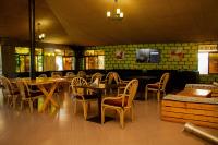 ein Restaurant mit Tischen und Stühlen und einem Fernseher in der Unterkunft Distinction Gardens in Siaya