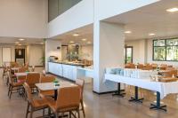 Un restaurante con mesas y sillas y una cocina. en Tri Hotel Antônio Prado, en Antônio Prado